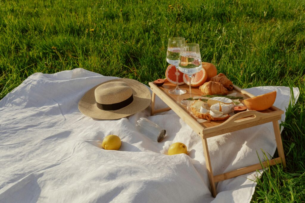 A delightful summer boutique picnic with cheese, pastries, and fruits on a grassy field.
