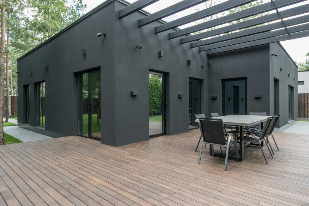 pexels-photo-7587854-7587854 Contemporary black house with spacious wooden terrace and outdoor seating area.