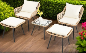 White rattan bistro outdoor chairs on a wooden patio surrounded by plants.