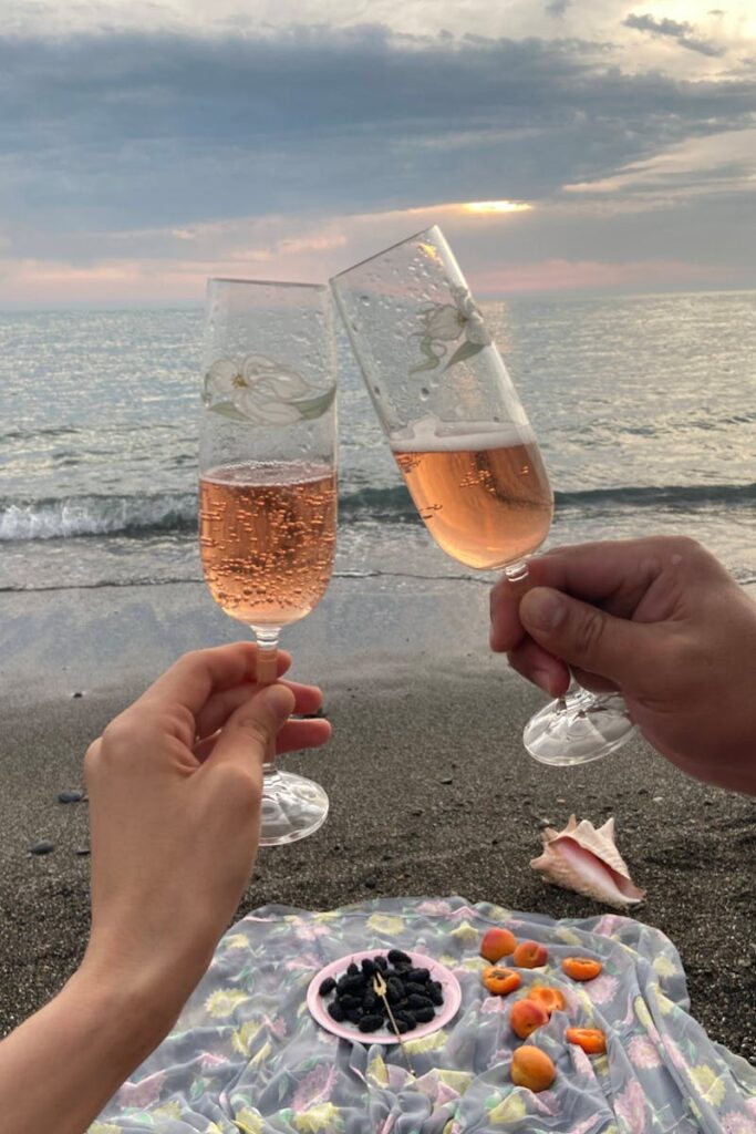 Couple toasting on a tranquil beach with champagne glasses, capturing a moment of romance at sunset.